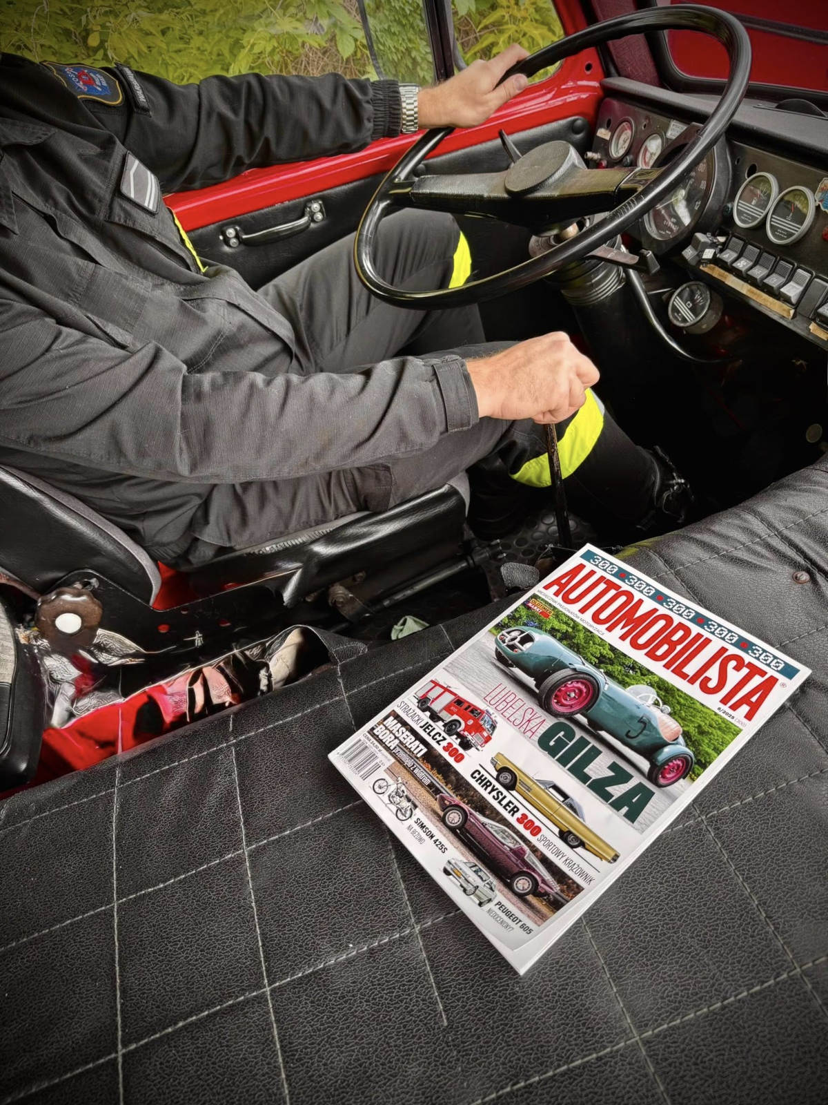 Wnętrze wozu strażackiego Jelcz z OSP Warszawa – Białołęka. Na fotelu pasażera leży magazyn Automobilista z okładką poświęconą pojazdom.