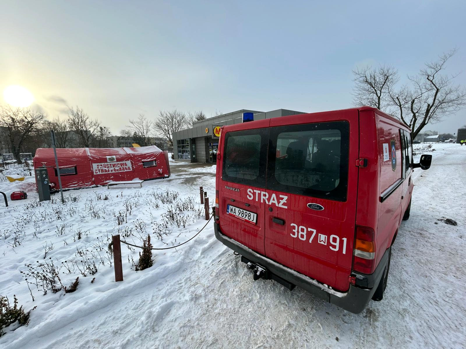 Strażacy z OSP Białołęka wspierają działania przy namiotach grzewczych. Na zdjęciu wóz strażacki oraz rozstawiony namiot ratowniczy w zimowej scenerii przy stacji metra.