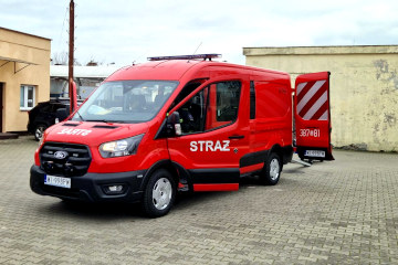 Nowy pojazd OSP Warszawa‑Białołęka marki Ford, zaparkowany przy budynku, z otwartymi tylnymi drzwiami i oznaczeniem 387[81].